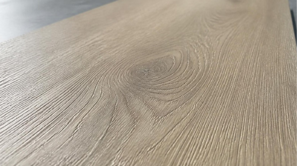 AI-generated editorial close-up of wood-look vinyl grain and shallow surface texture under grazing light; not a verified EIR product sample.